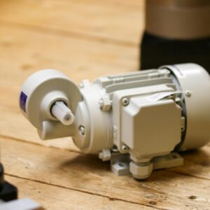 Close-up of a white industrial motor placed on a wooden surface inside a workshop.